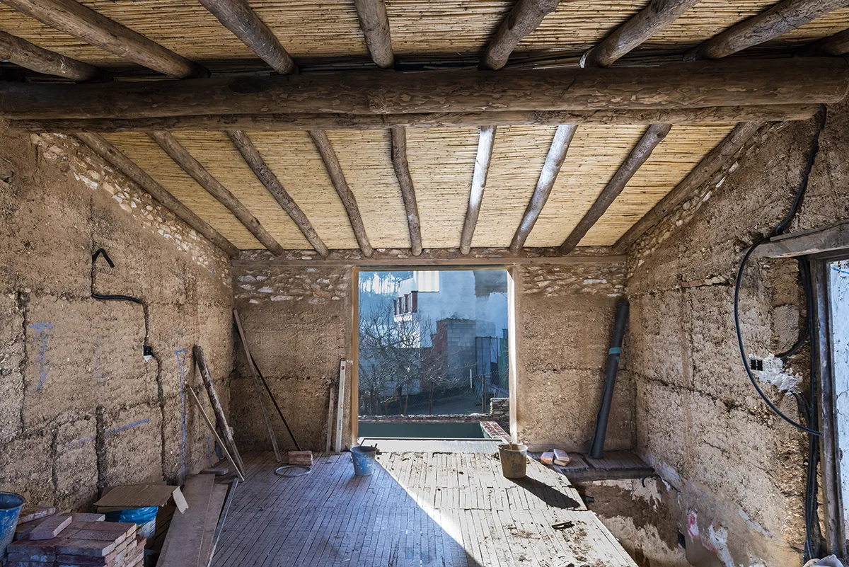 Interior del Proyecto Alondra durante la rehabilitación, con muros de tapial, estructura de madera y cubierta tradicional de cañizo.