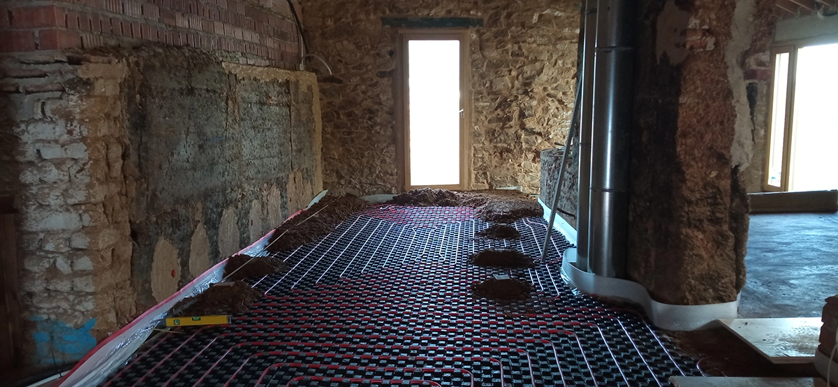 Ejecución de un suelo continuo de tierra prensada durante la rehabilitación de La Posada, conservando la arquitectura tradicional y los muros de tapial.