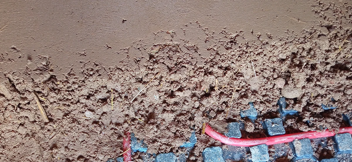 Detalle de la ejecución de un suelo continuo de tierra prensada durante la rehabilitación de una vivienda tradicional.