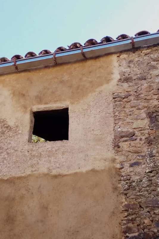 Fachada de vivienda tradicional rehabilitada con revoco de cal y mampostería vista en la Sierra de Aracena.